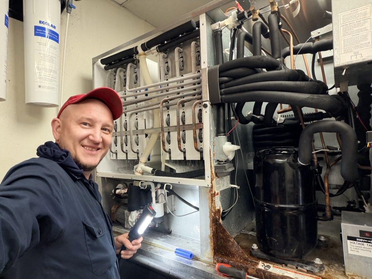 AC/DC technician diagnosing a commercial ice machine and its refrigeration system on site in DFW