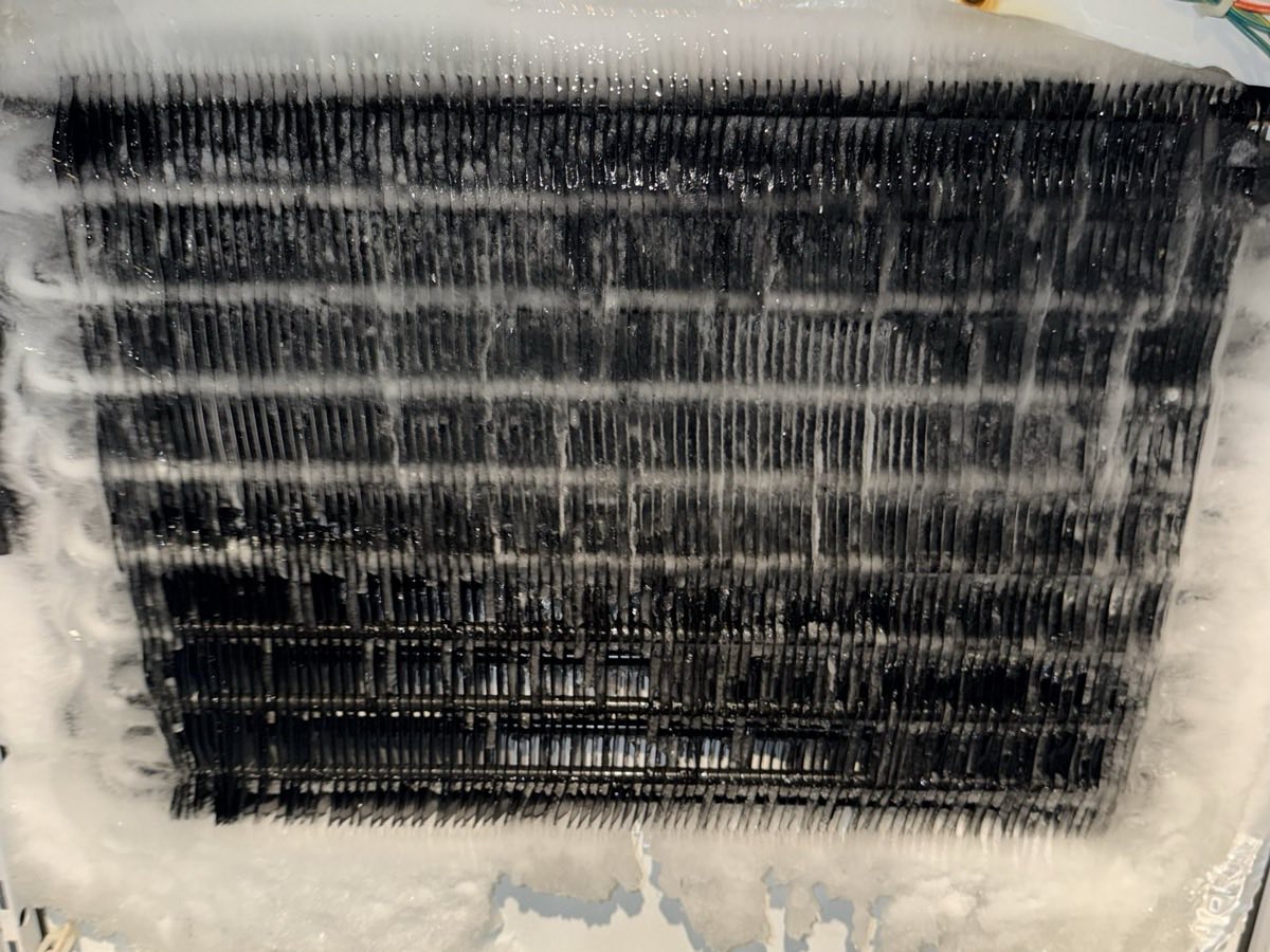 Evaporator coil of a built-in refrigerator completely encased in frost, photographed during a service call
