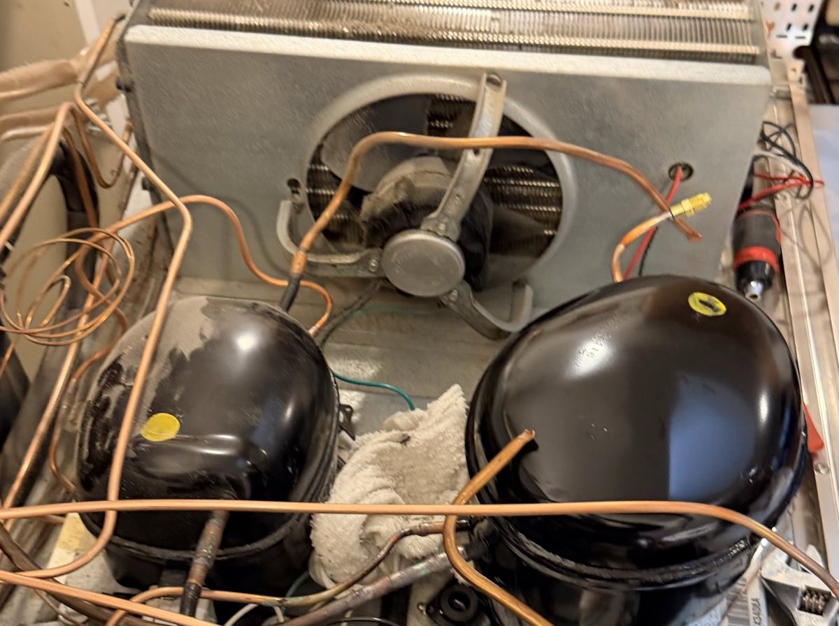 Machine compartment of a dual-compressor built-in refrigerator with both compressors, condenser coil and fan exposed for service