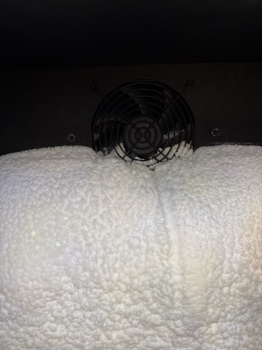Freezer evaporator fan grille almost buried under a mound of frost