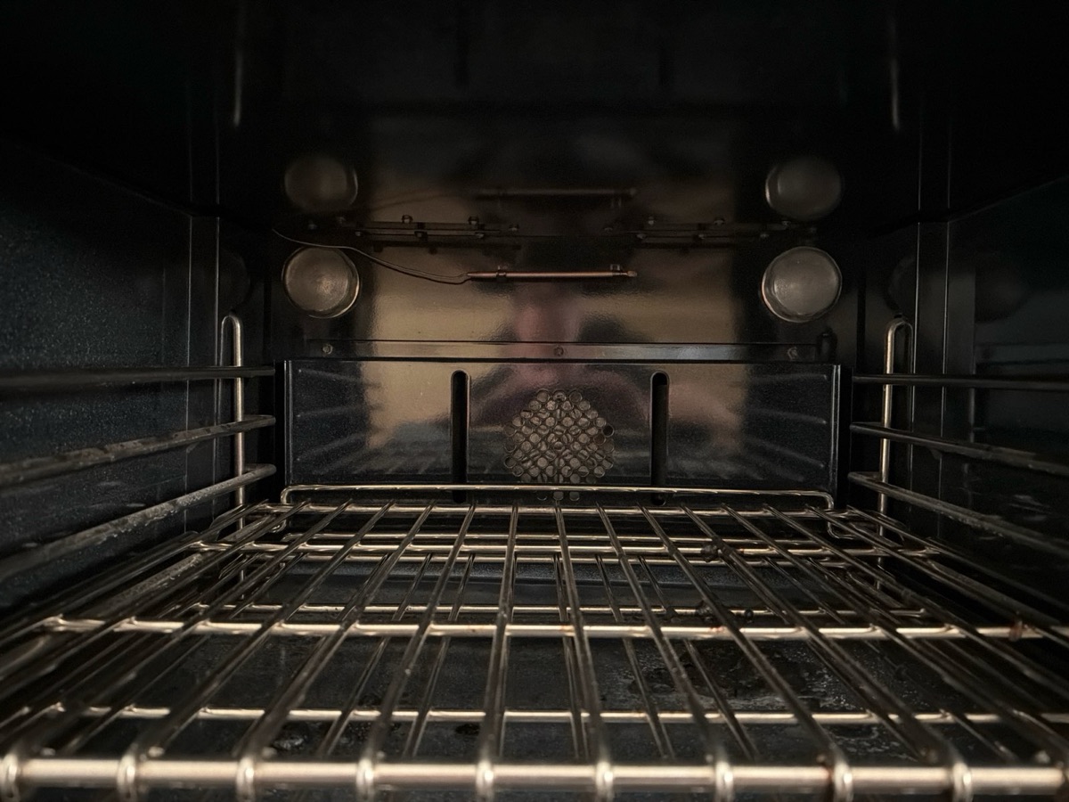 Inside a professional gas oven cavity with the convection fan cover, oven lights and temperature sensor on the back wall