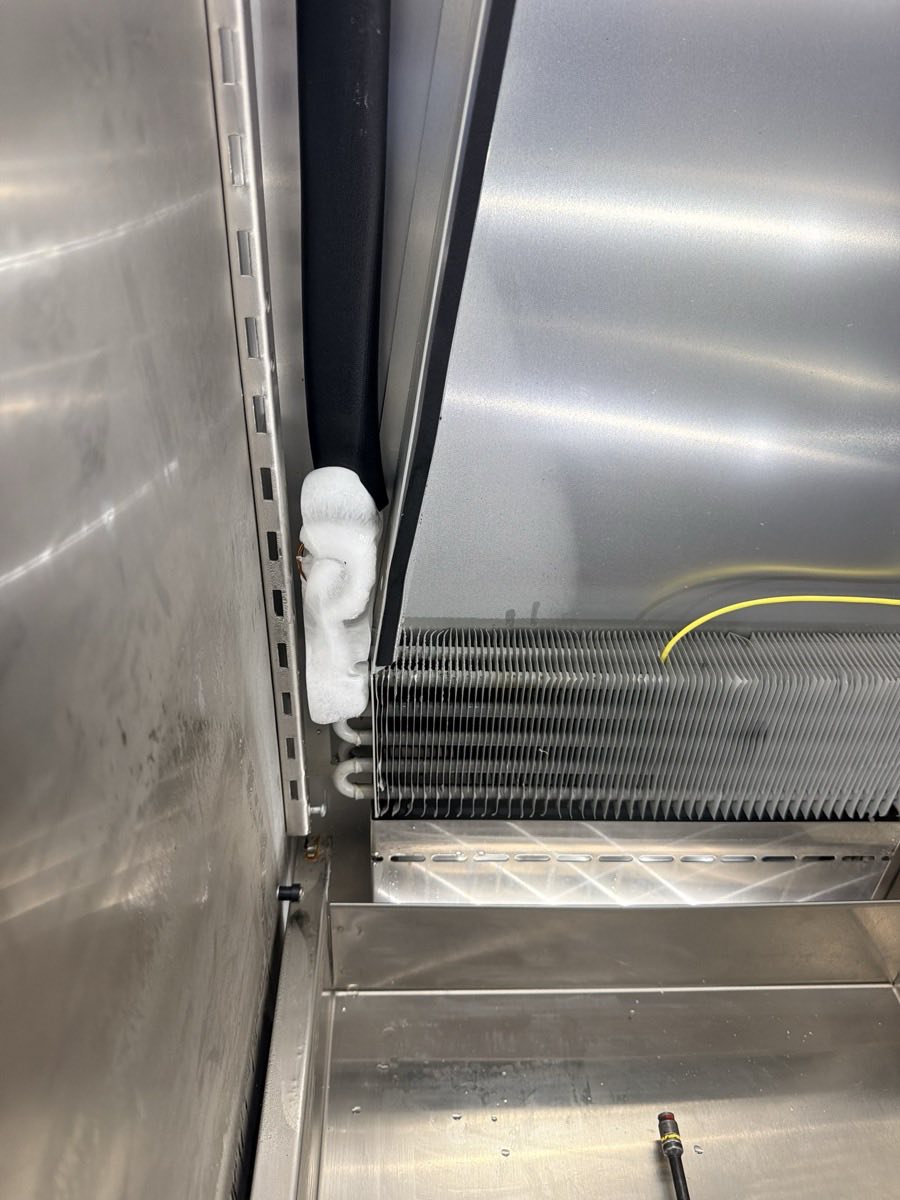 Reach-in refrigerator interior with the evaporator coil and a frosted suction line exposed for service