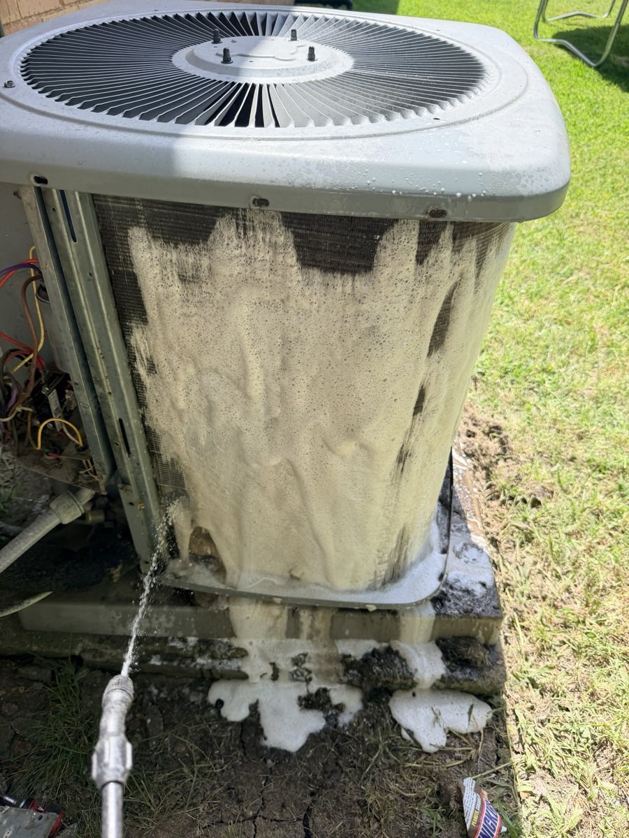 Foaming coil cleaner being rinsed from the fins of a residential outdoor air conditioning condenser