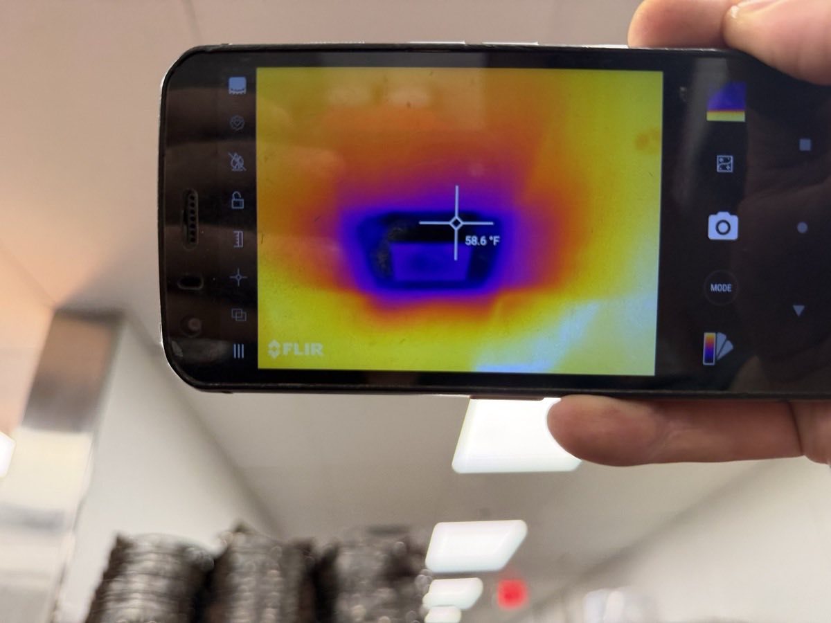 Technician using a FLIR thermal imaging camera to read surface temperature during an appliance diagnosis