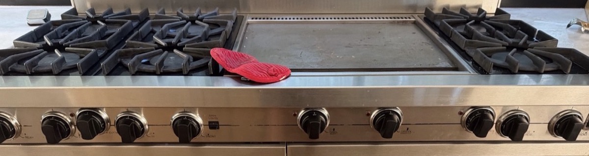 Sealed burners under cast-iron grates and a centre griddle on a Viking Professional range, control knobs below