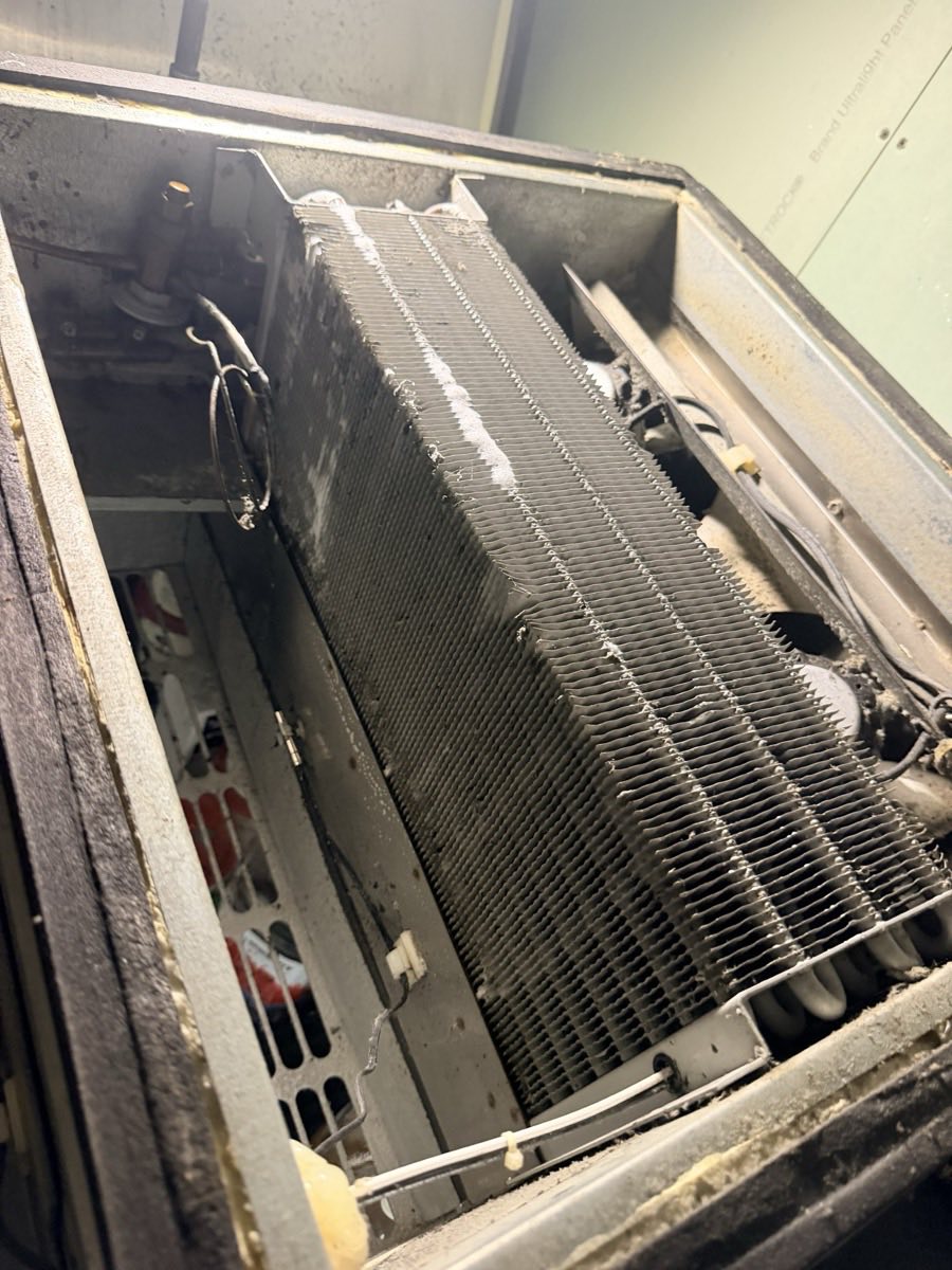 Walk-in cooler evaporator unit opened for service, showing frost across the coil fins