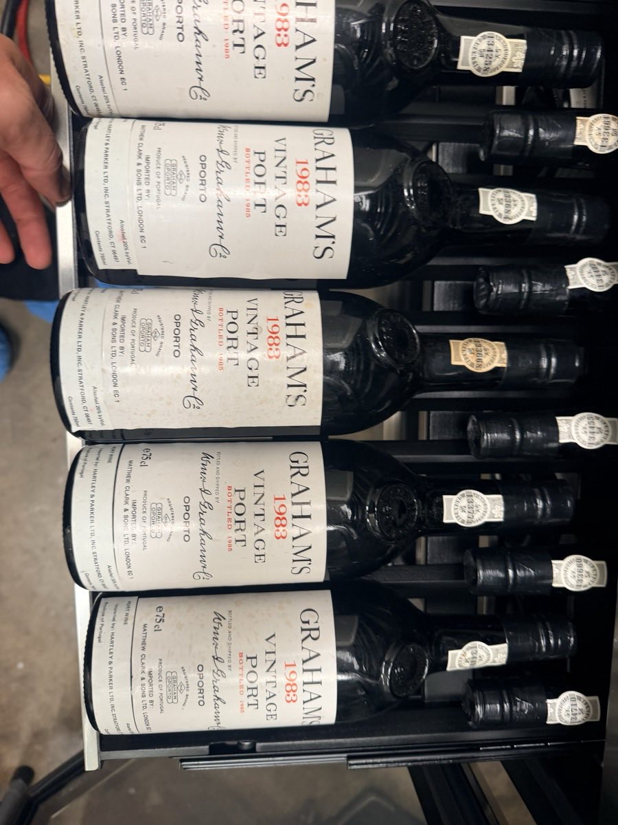 Vintage port bottles from 1983 racked inside a wine refrigeration unit during a service call in DFW